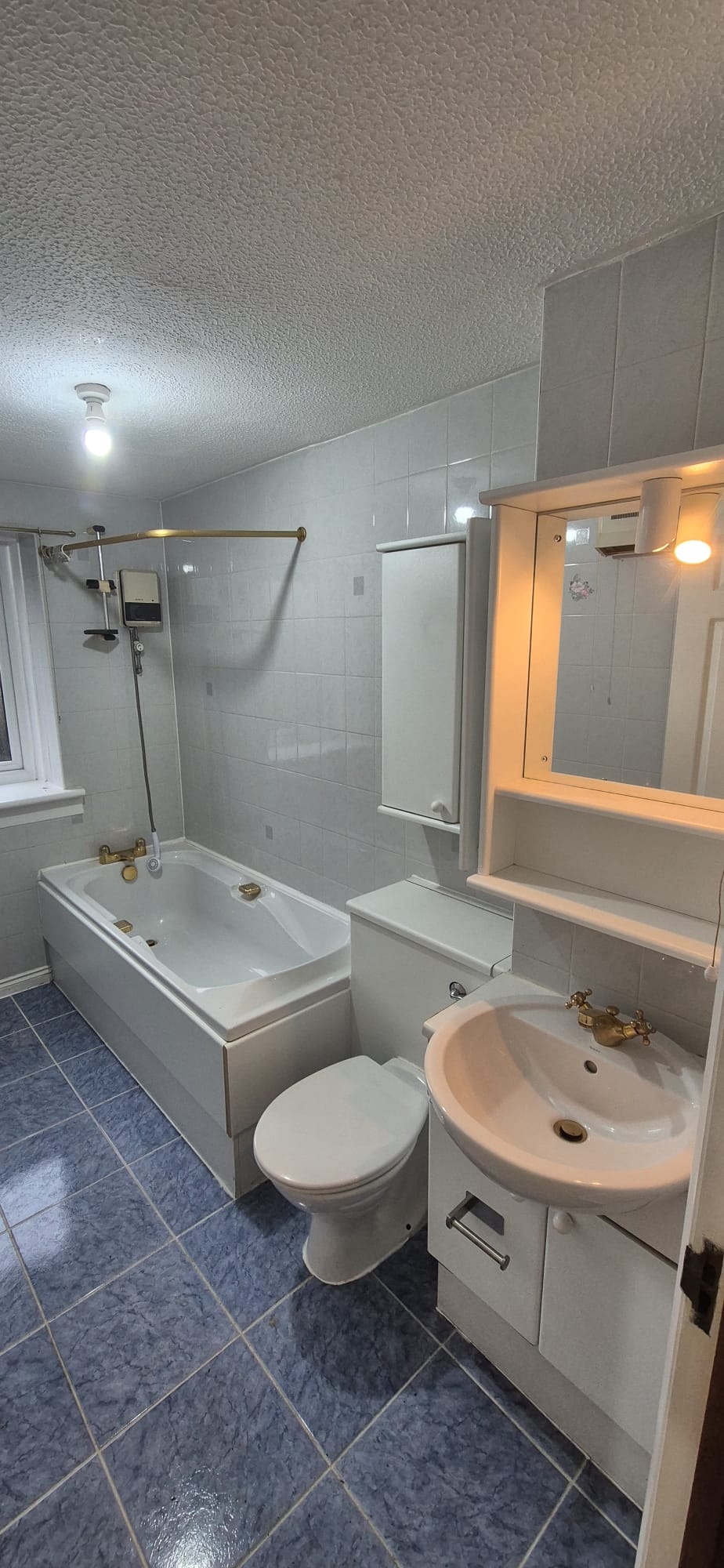 Dated bathroom with white tiling and blue floor before renovation