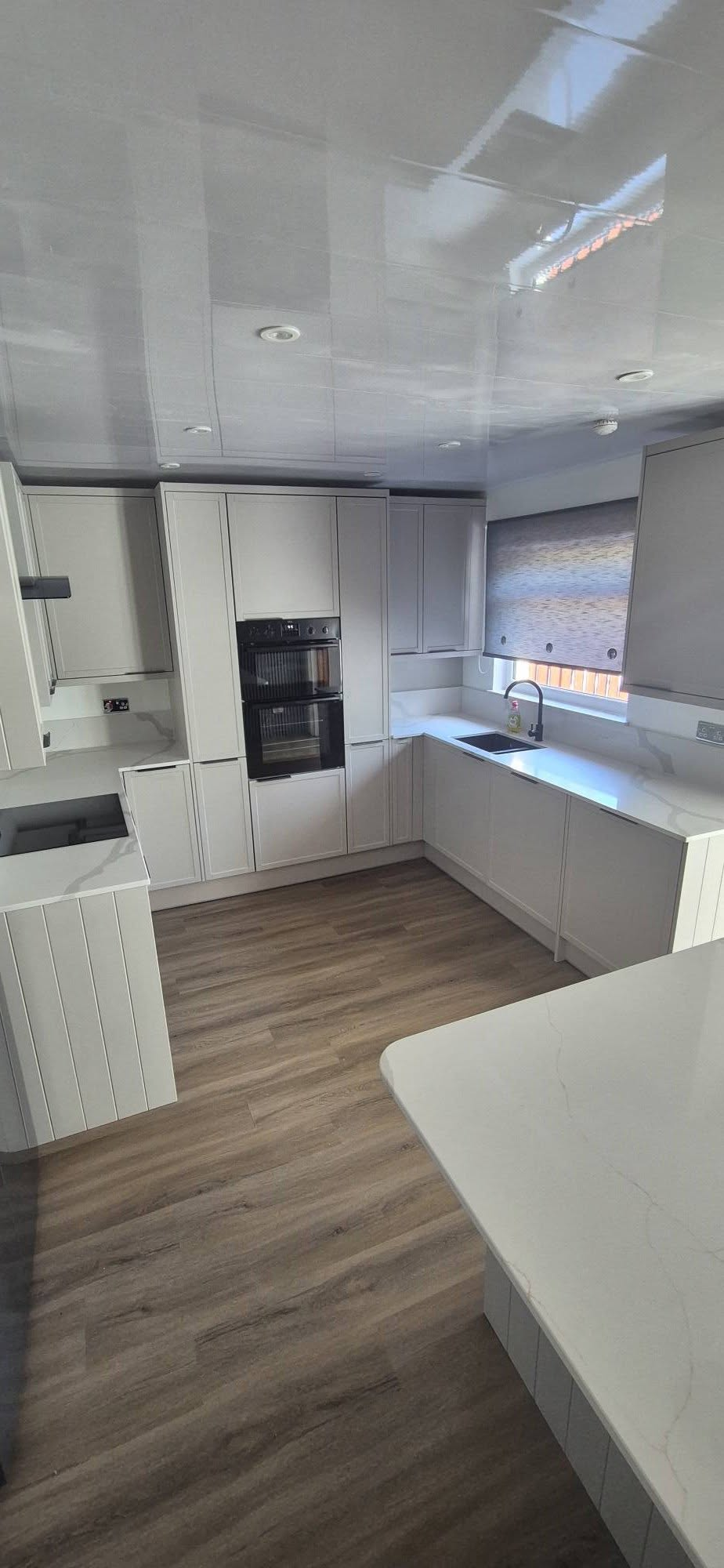 New light grey shaker kitchen with quartz worktops, integrated double oven and gloss stretch ceiling