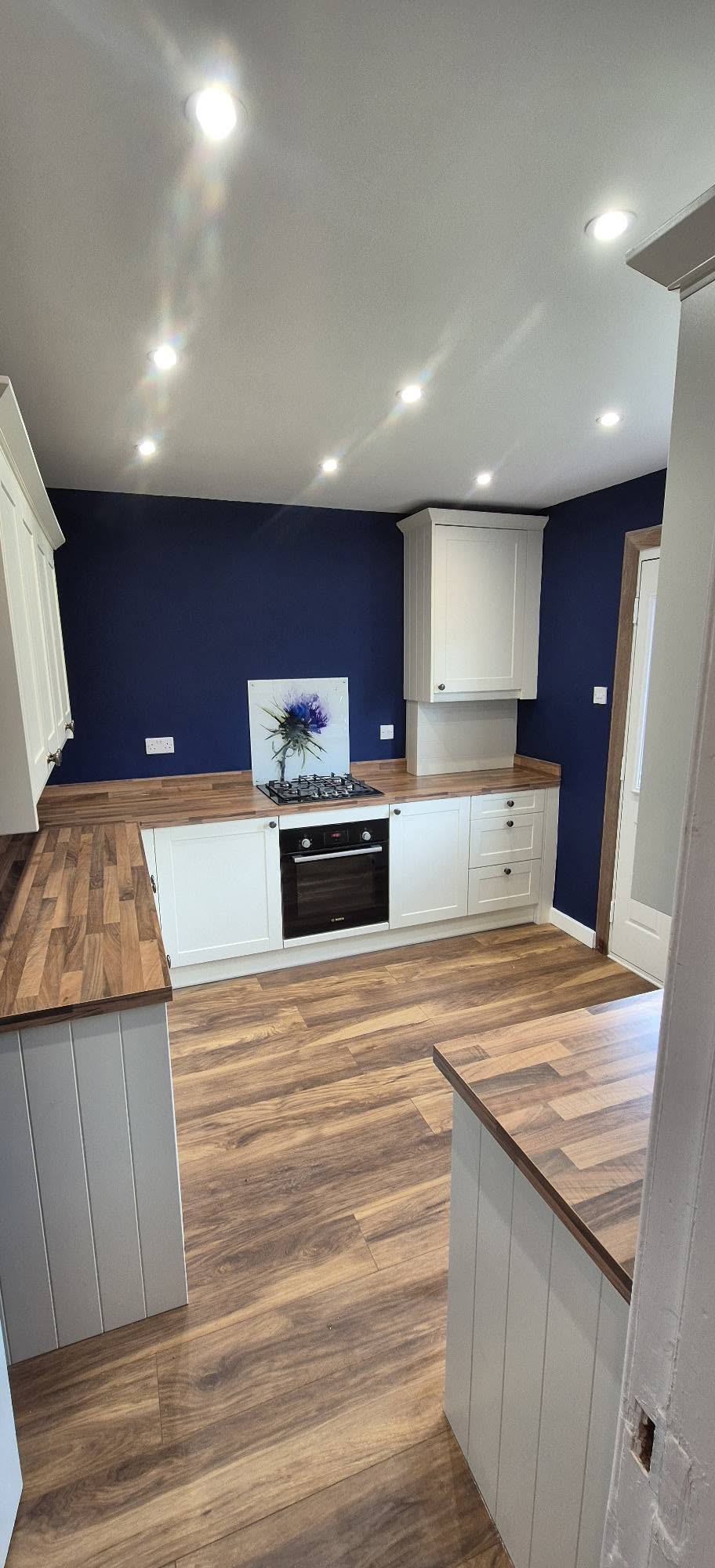 New shaker kitchen with cream units, wood worktops, navy walls and integrated oven
